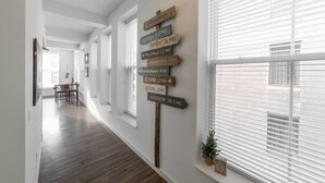 A hallway with wooden flooring and a wall-mounted signpost indicating distances to various local destinations. - 725- Big 2 bedroom/king beds/Corner Unit/ + parking (Milwaukee)