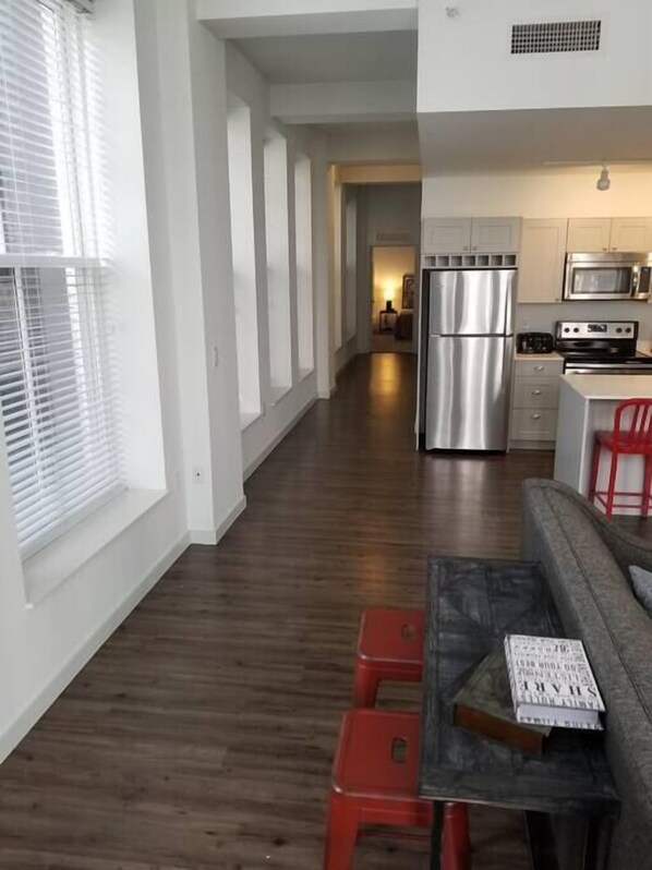 A modern kitchen with stainless steel appliances, a dining area with a table and red chairs, and a hallway leading to another room. - 325- Big Corner condo w/2 king bedrooms/Free parking (Milwaukee)