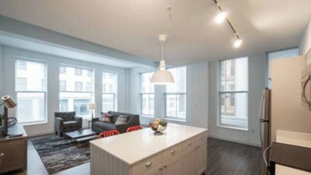 A modern kitchen with a central island, large windows, and a dining area with a sofa and chairs. - 325- Big Corner condo w/2 king bedrooms/Free parking (Milwaukee)