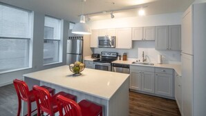 A modern kitchen with white cabinets, stainless steel appliances, and a central island with red chairs. - 325- Big Corner condo w/2 king bedrooms/Free parking (Milwaukee)