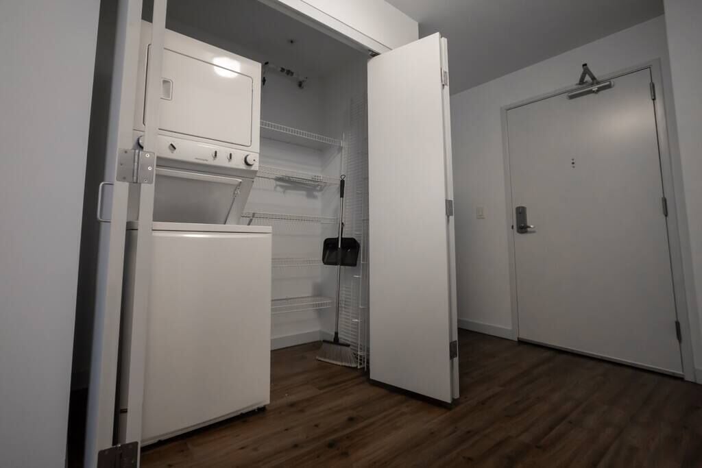 Cuina compacta amb nevera, forn i microones. Una escombra recolzada a la paret.