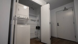 A compact kitchen with a refrigerator, oven, and microwave. A broom is leaning against the wall. - 325- Big Corner condo w/2 king bedrooms/Free parking (Milwaukee)