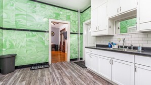 Una cocina con baldosas de mármol verde, armarios blancos y encimera negra.