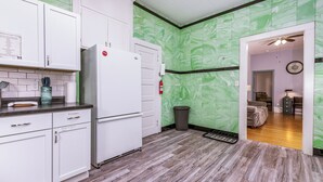 Una cocina con armarios blancos, un refrigerador blanco y un salpicadero de mármol verde.
