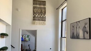 A narrow hallway with dark wooden floors, a wooden table with stools, a hanging tapestry, and a framed horse painting on the wall. - 302/303- 2 condos joined for up to 12 people by Fiserv/3rd (Milwaukee)