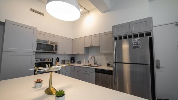 A modern kitchen with white cabinets, stainless steel appliances, and a central island with a unique airplane sculpture.