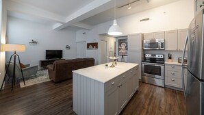A modern kitchen with white cabinets, stainless steel appliances, and a central island.