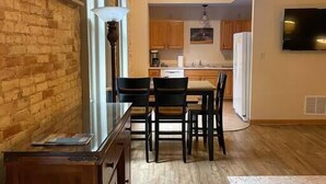 Una cocina con armarios de madera, una mesa de comedor con sillas y un refrigerador.