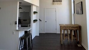 A narrow hallway with a ceiling fan, a kitchen area with a built-in oven, and a dining table with stools.