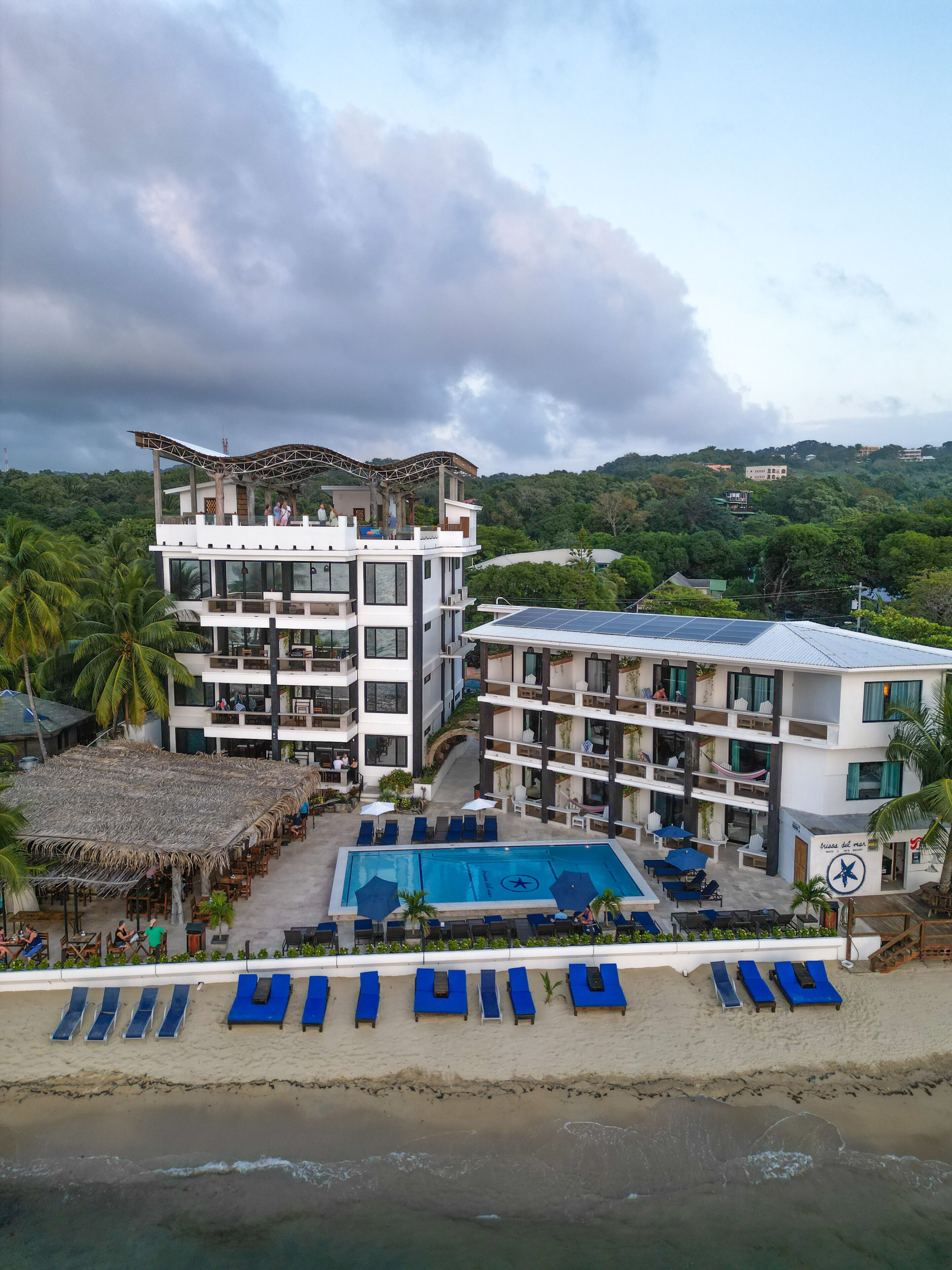 Un resort con piscina, varias plantas y zona de playa.