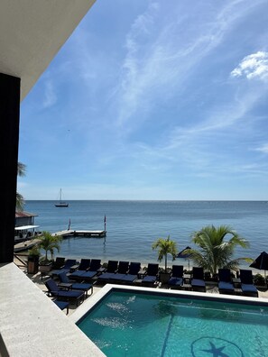 A pool area with lounge chairs and a view of the sea.