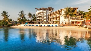 Un resort con piscina, sillas de playa y un edificio con varios balcones.