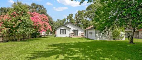 A single-story house with a front porch, surrounded by a well-maintained lawn and trees.