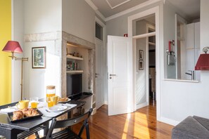 A dining area with a table set for breakfast, a coffee machine, and a television.