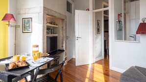 A dining area with a table set for breakfast, a coffee machine, and a television.