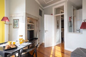 A dining area with a table set for breakfast, a coffee machine, and a television.