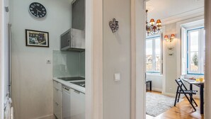 A kitchen with white cabinets, a dishwasher, and a clock on the wall.