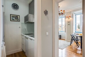 A kitchen with white cabinets, a dishwasher, and a clock on the wall.