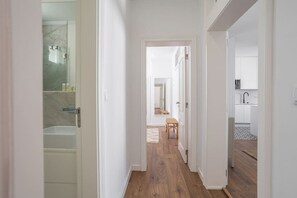 A hallway leading to a bathroom with a glass shower enclosure and a visible sink.