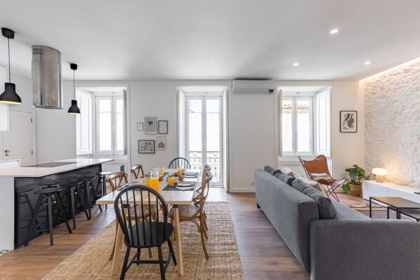 A modern kitchen with a dining area, a sofa, and a stone accent wall.