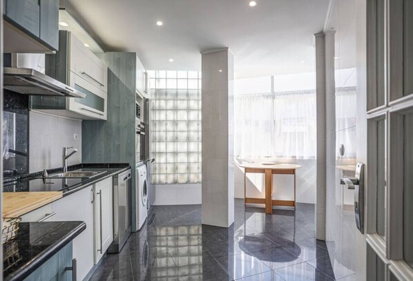 Enjoy cooking in this well-equipped kitchen with a stainless steel range hood, washing machine, and ample counter space.