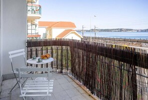 Enjoy the ocean view from this balcony with a table and chairs.