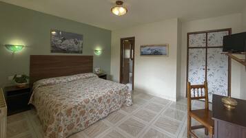 A bedroom with a bed, bedside tables, a television, and decorative wall lights.
