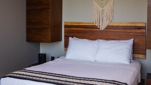 A neatly made bed with a wooden headboard and a macrame wall hanging. - LUXURIOUS 2 STORY PH / PREMIUM AREA / PRIVATE PLUNGE POOL / HEART OF ALDEA ZAMA (Q.R.)