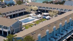 A coastal hotel with multiple buildings, a marina, and a view of the sea. - Charming Waterfront Retreat with pool & short stroll to beach! (Ocean City)