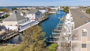 A canal with houses on one side and a dock with boats on the other. - Charming Waterfront Retreat with pool & short stroll to beach! (Ocean City)