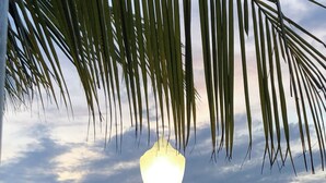 A lamp post with a light, palm trees, and a body of water during sunset. - Charming Waterfront Retreat with pool & short stroll to beach! (Ocean City)