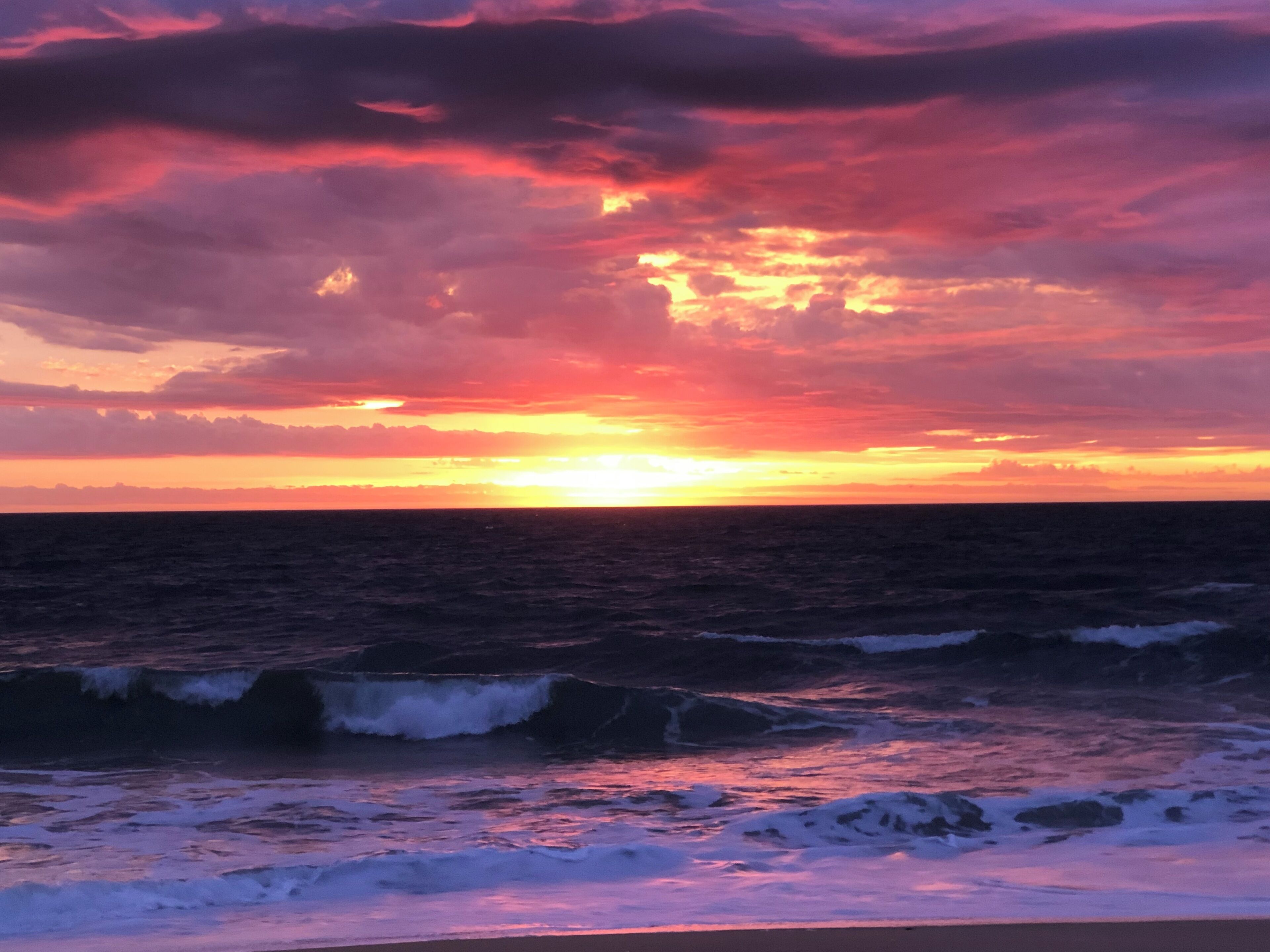 A sunset over the ocean with waves.