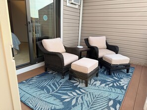 A patio area with wicker furniture, a glass door, and a patterned rug.