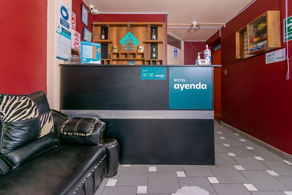 A reception area with a black counter, a leather sofa, and a wooden display shelf. - Hospedaje Muñoz (Ica)