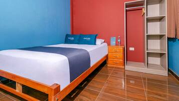 Una habitación de hotel con cama, armario y mesita de noche.