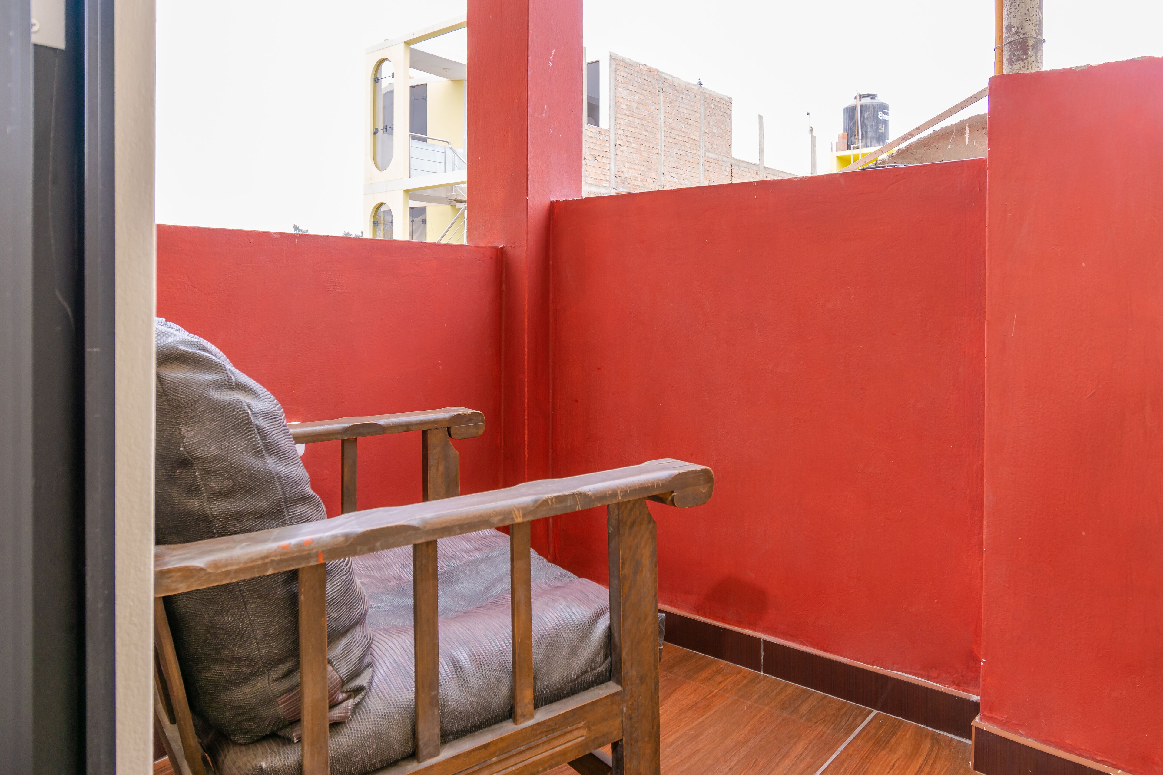 A red-walled room with a wooden chair and a cushion.