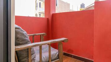 A red-walled room with a wooden chair and a cushion.