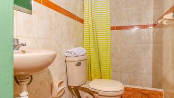 Baño con lavamanos, inodoro y cortina de ducha.