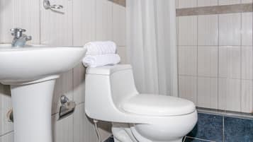 Un baño con lavamanos blanco, inodoro y suelo con azulejos azules.