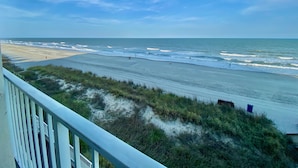 A beach view from a balcony with a railing, sandy beach, and ocean waves. - Luxury Direct Ocean Front- 3 bed-3 bath with Large Balcony<br>One Ocean Place (Murrells Inlet)