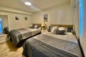 Une chambre d’hôtel avec deux lits, une table de chevet avec une lampe et un tableau accroché au mur.