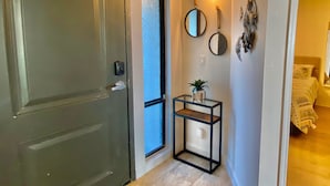 A hallway with a closed door, a small table with a plant, and a wall-mounted mirror. - Luxury Direct Ocean Front- 3 bed-3 bath with Large Balcony<br>One Ocean Place (Murrells Inlet)