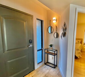 A hallway with a closed door, a small table with a plant, and a wall-mounted mirror. - Luxury Direct Ocean Front- 3 bed-3 bath with Large Balcony<br>One Ocean Place (Murrells Inlet)