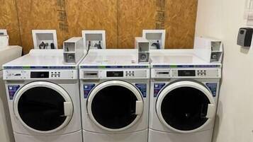 A row of three front-loading washing machines in a commercial setting.