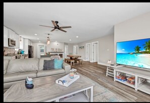Relax in a spacious living area with a large flat-screen TV, comfortable seating, and a dining table.