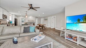 A modern living room with a sofa, coffee table, and TV. - Large newly renovated family home. Sleeps 15. Walking distance to everything. (Oak Island)