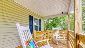 A covered porch with wooden railings and two white rocking chairs. - Large newly renovated family home. Sleeps 15. Walking distance to everything. (Oak Island)