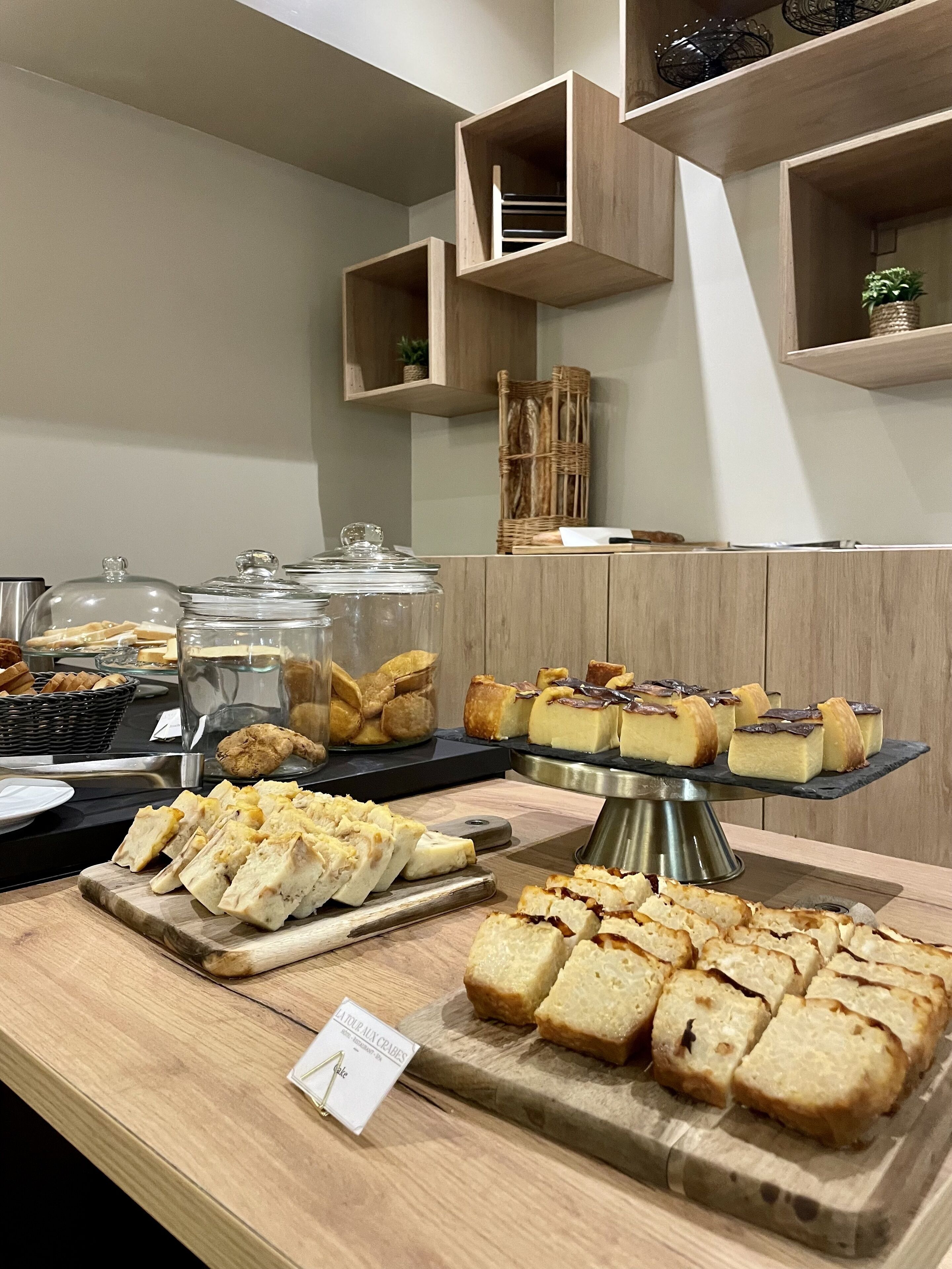 A buffet with various cheeses, breads, and pastries.