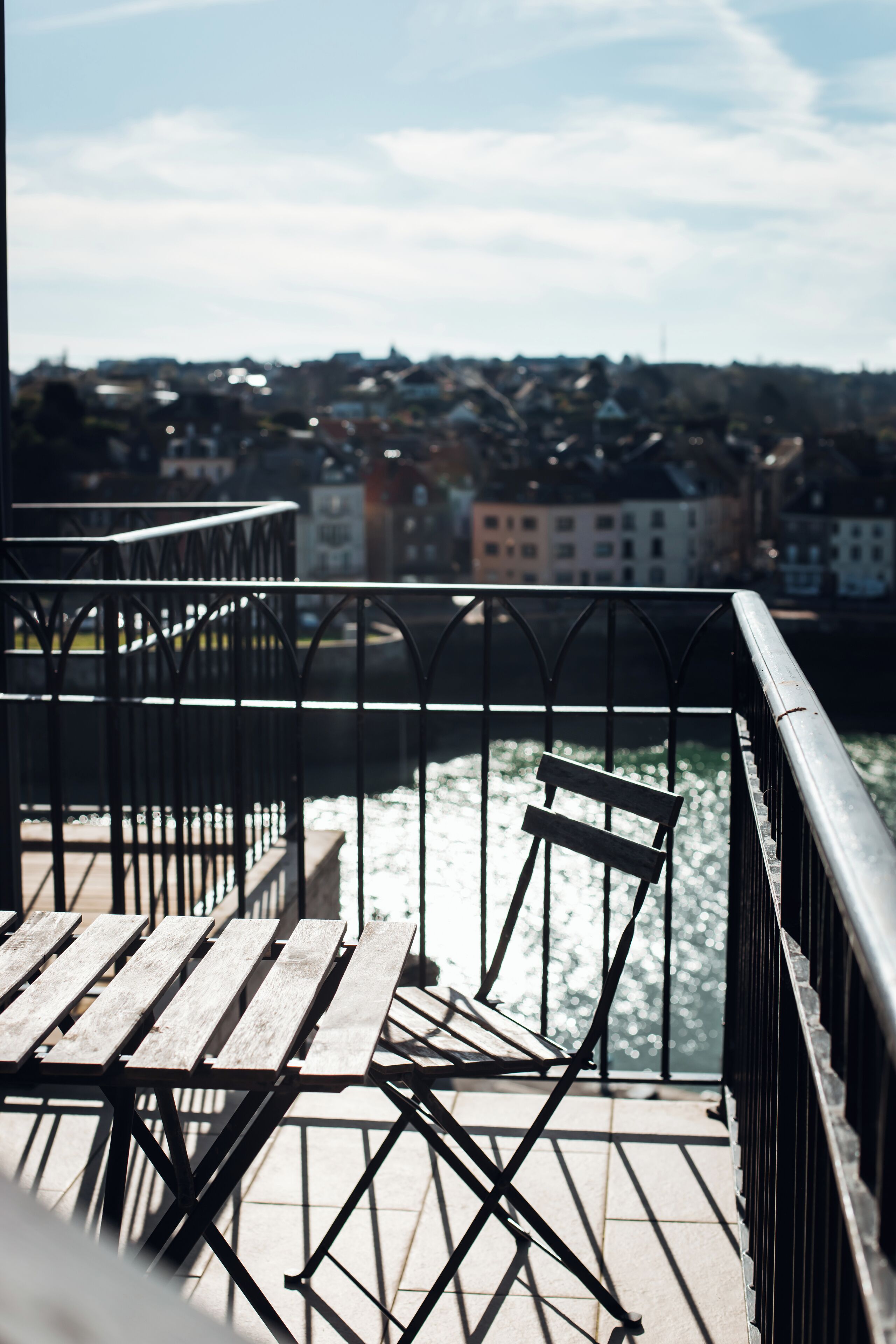 A balcony with metal railings overlooking a river and a cityscape.
