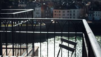 A balcony with metal railings overlooking a river and a cityscape.